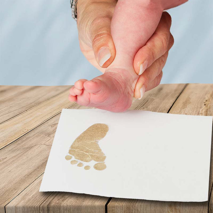 Inkless print kit showing baby's foot print using bronze ink.