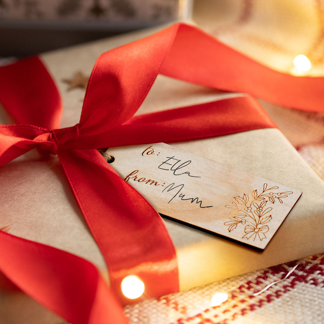 Closeup of non-custom Christmas gift tag with holly design etched into wood.