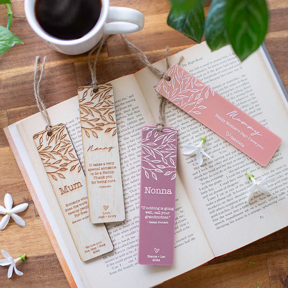 Top view of set of four custom Hello Fern Mother's Day bookmarks on book with flowers and tea.