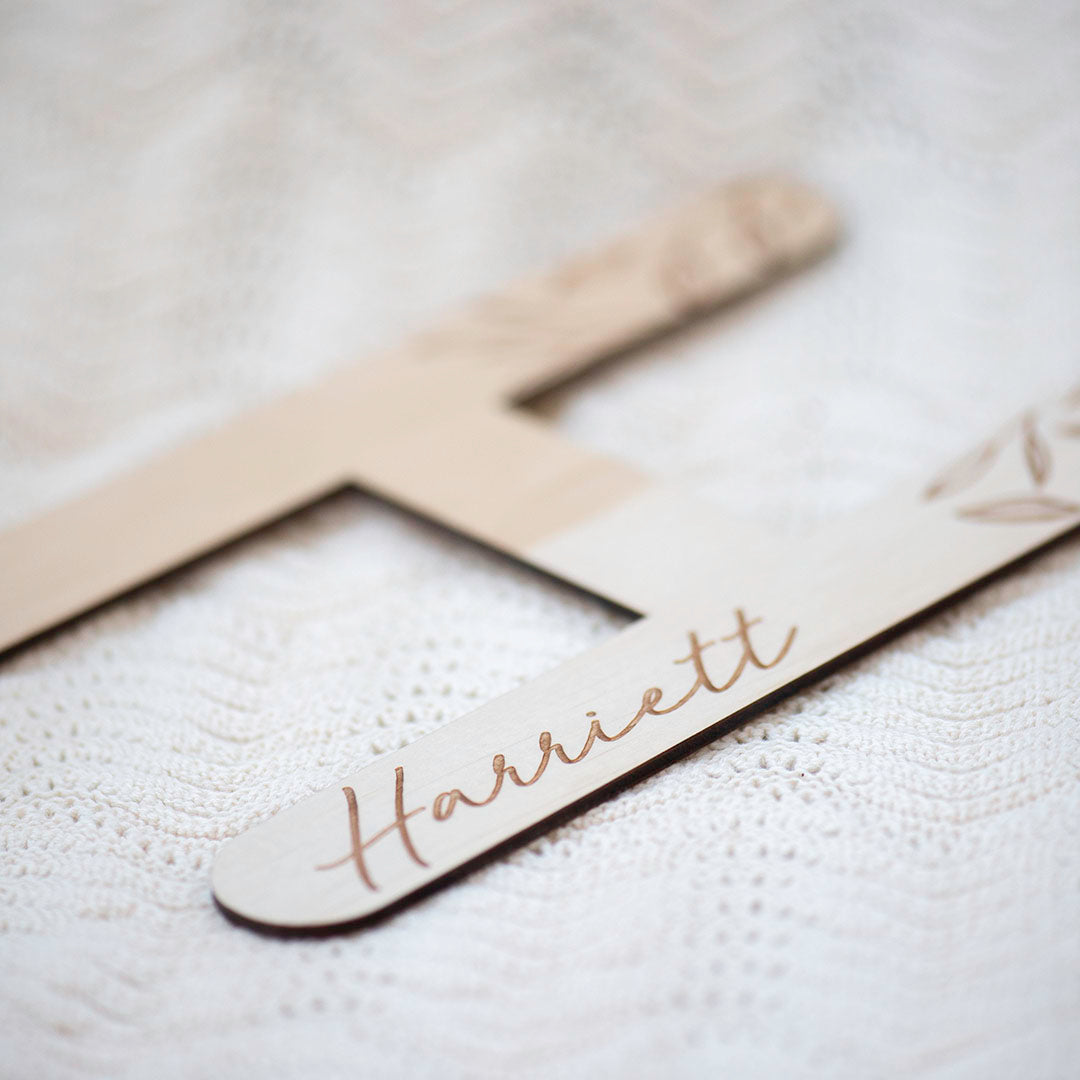 Hello Fern custom etched wooden wall letter, letter 'H' for 'Harriett' shown closeup on blanket.