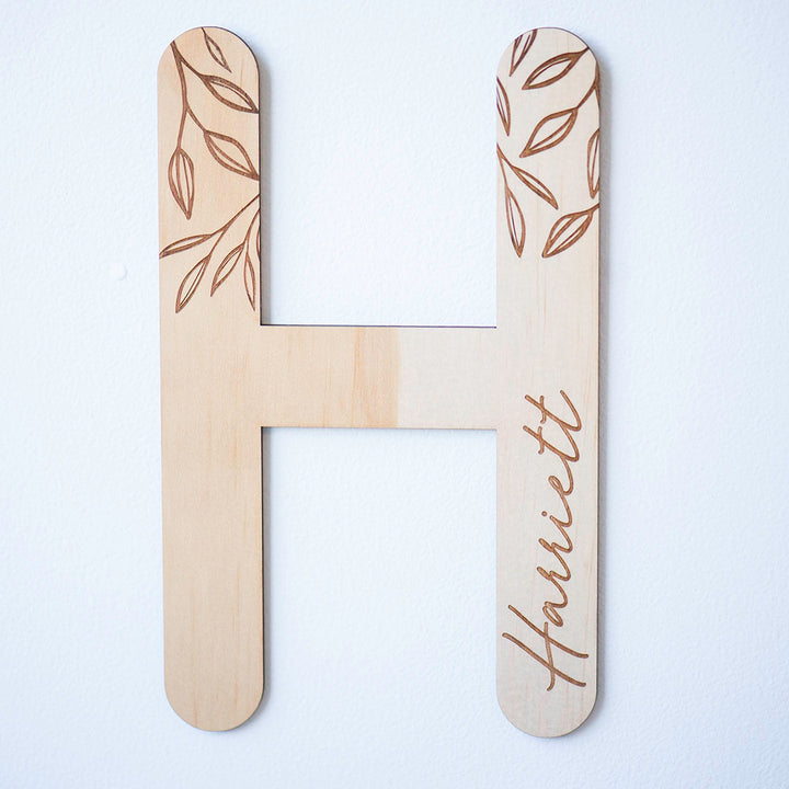 Hello Fern personalised wooden wall letter, letter 'H' for 'Harriett' shown hanging on white wall.