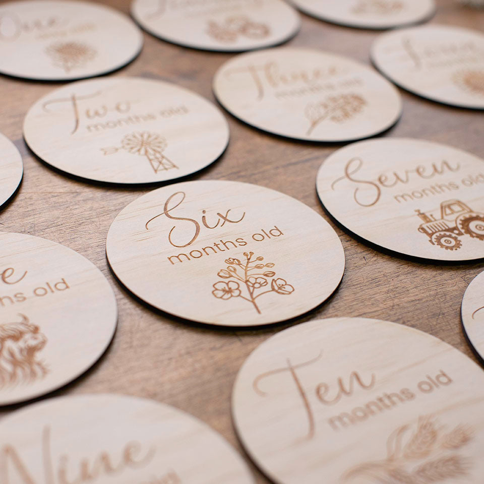 Closeup view of Six months old disc from the Hello Fern Country Month Milestone wooden disc set for baby.