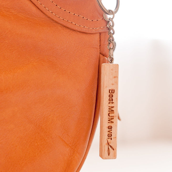 Closeup of Hello Fern light wooden Mother's Day keyring hanging from brown leather bag.