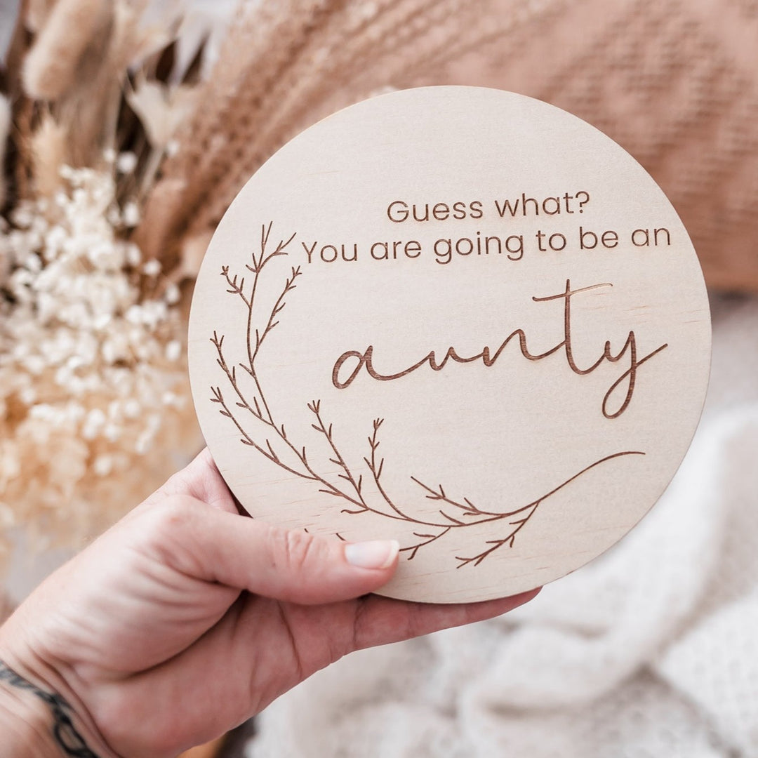 Woman's hand holding Hello Fern announcement plaque - Guess what? You are going to be an aunty.