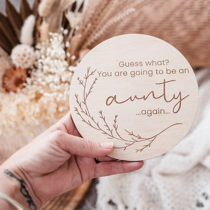 Woman's hand holding Hello Fern announcement plaque - Guess what? You are going to be an aunty...again...