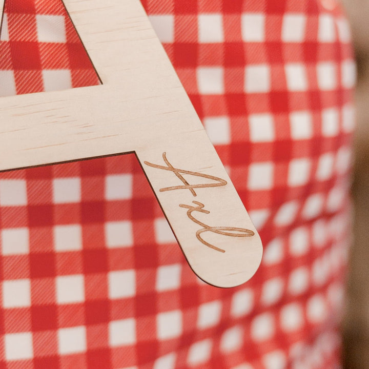 Closeup of red Christmas Santa sac with wooden letter 'A' plaque and name 'Axl' etched into plaque.