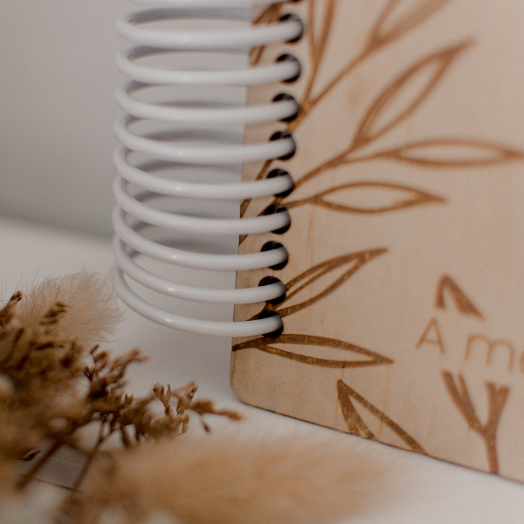 Closeup of white spiral used to bind Hello Fern wooden baby memory books.