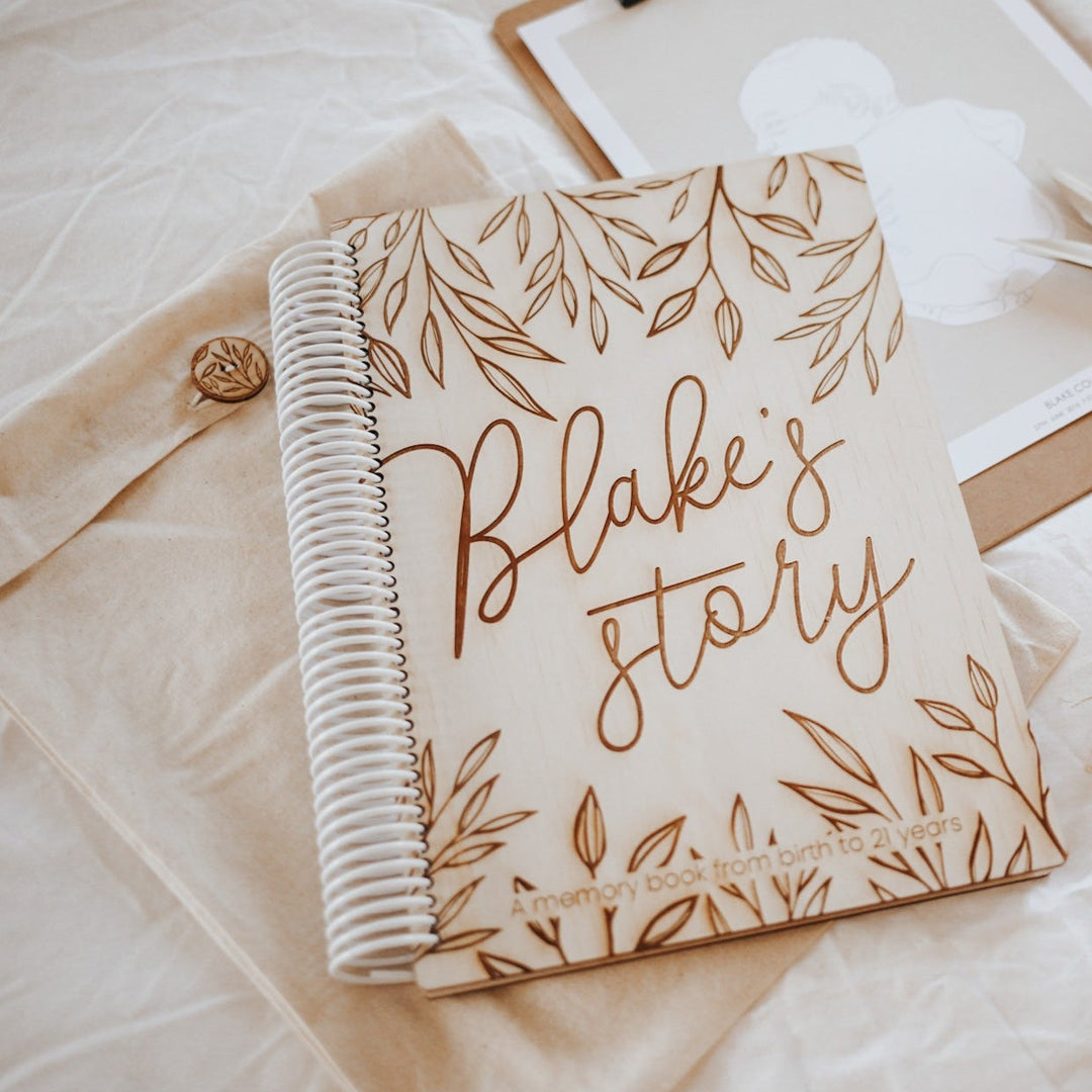 Custom Hello Fern wooden baby memory book with words 'Blake's story' etched onto cover.