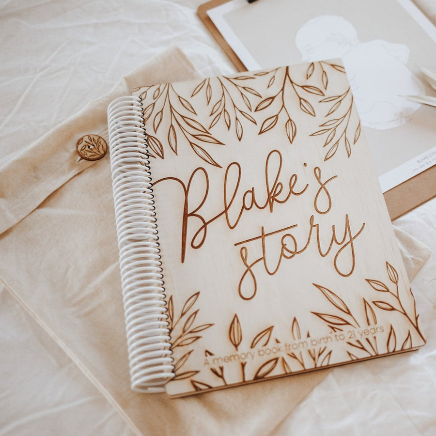 Custom Hello Fern wooden baby memory book with words 'Blake's story' etched onto cover.