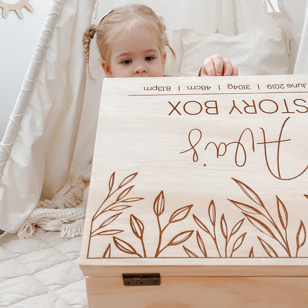 A child is opening her large wooden keepsake box and peering in.