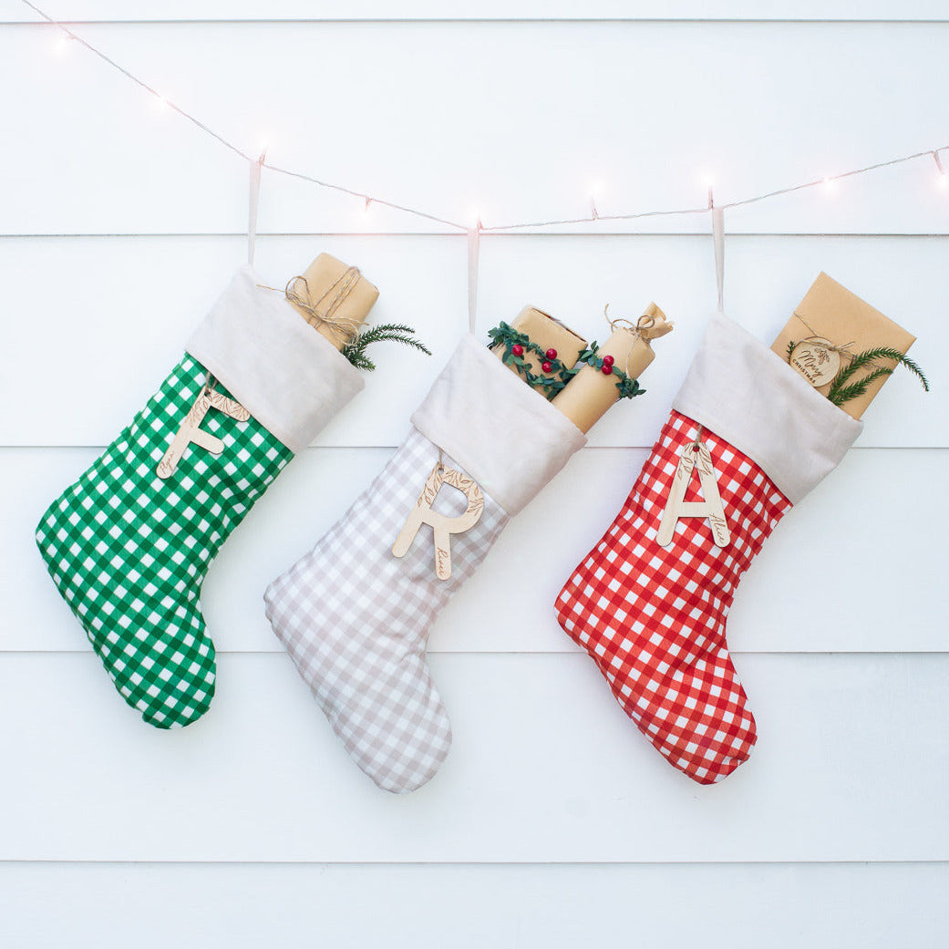 Three gingham Christmas stockings in green, brown, and red with custom letter name plaque