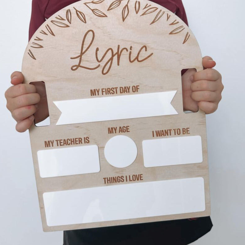 Primary-school-aged girl holding custom Hello Fern Back to School board with name Lyric at the top.