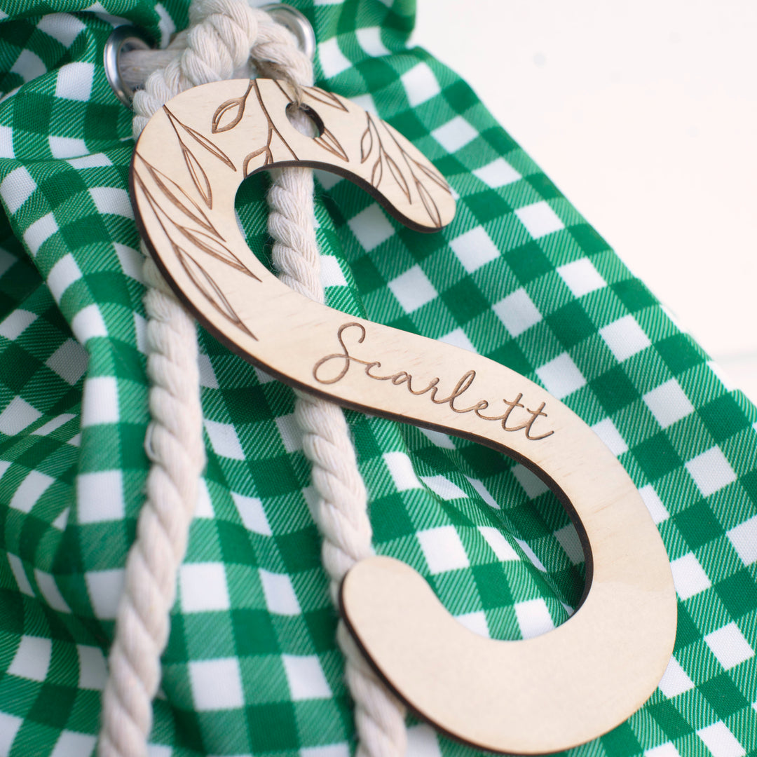 Closeup of green Christmas Santa sac with wooden letter 'S' plaque and name 'Scarlett' etched into plaque.