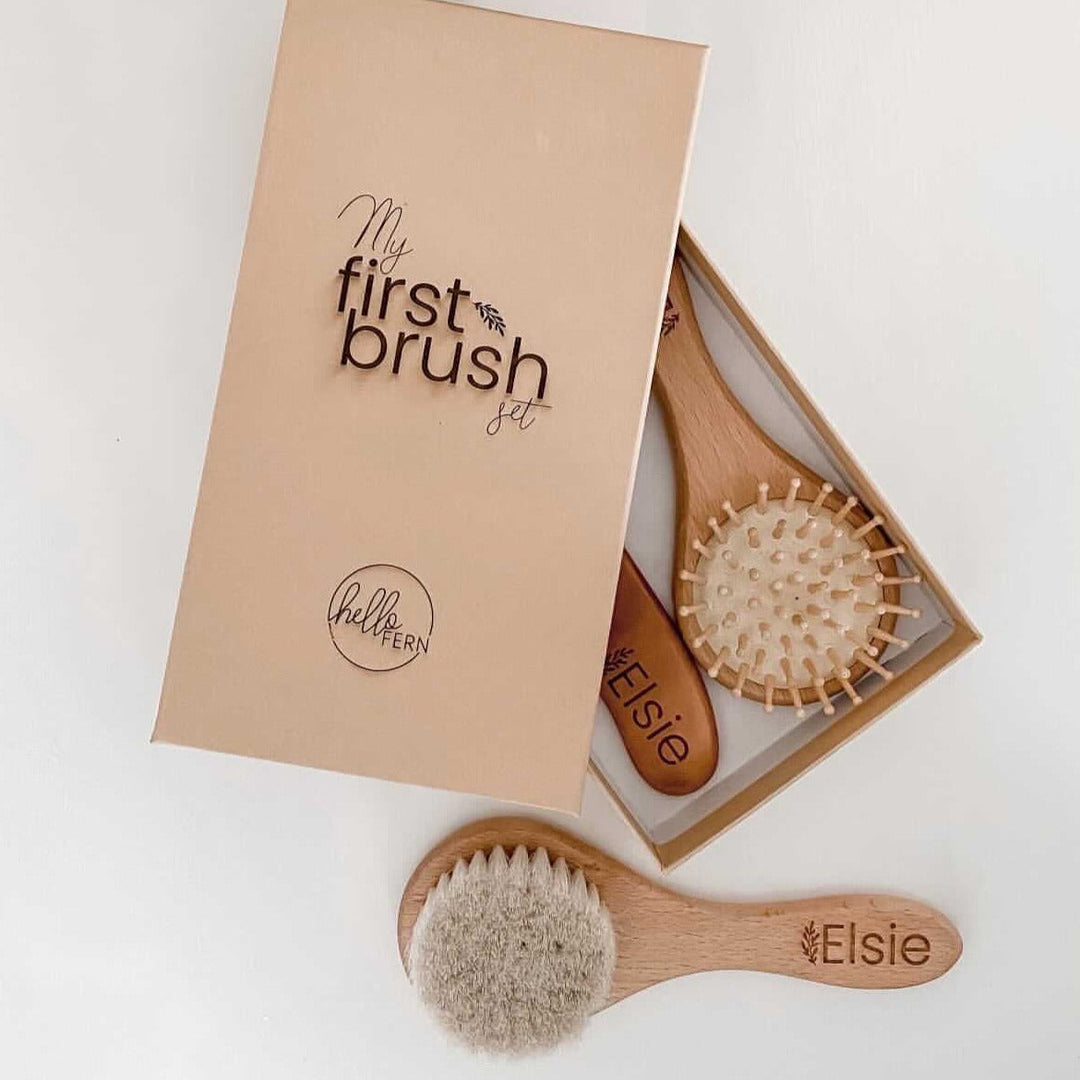 Flatlay showing three Hello Fern custom baby brushes with etched names on the handle with box storage option.