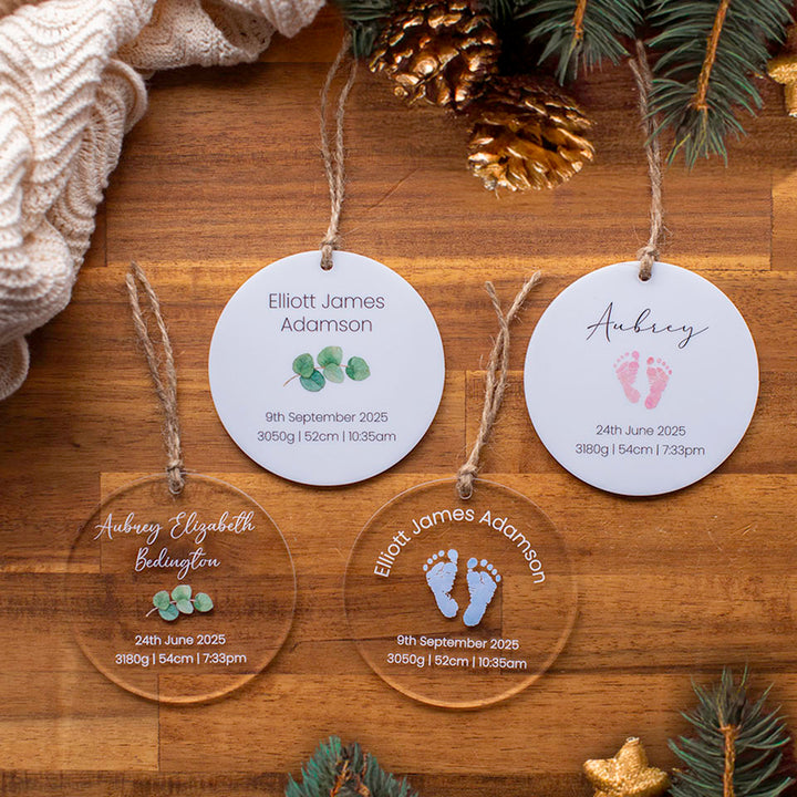 Four Hello Fern personalised acrylic baby Christmas ornament discs custom printed with birth details on a wooden surface with decorative elements.