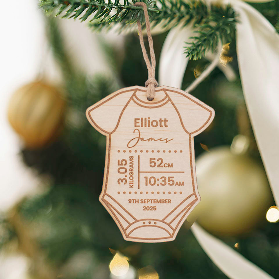 Hello Fern custom wooden baby onesie ornament with engraved name and birth details on a Christmas tree.