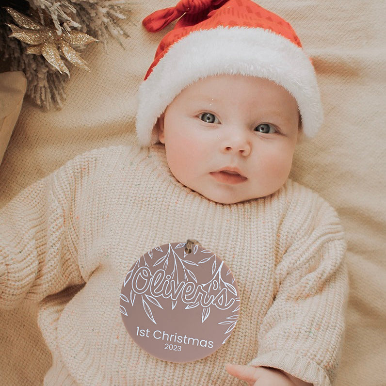 Baby with Santa hat lying on blanket with Hello Fern customisable 1st Christmas acrylic plaque.