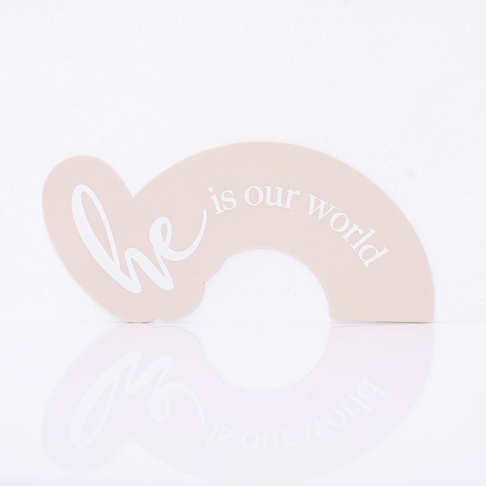 Hello Fern beige acrylic arch-shaped birth announcement plaque printed with the words "he is our world".