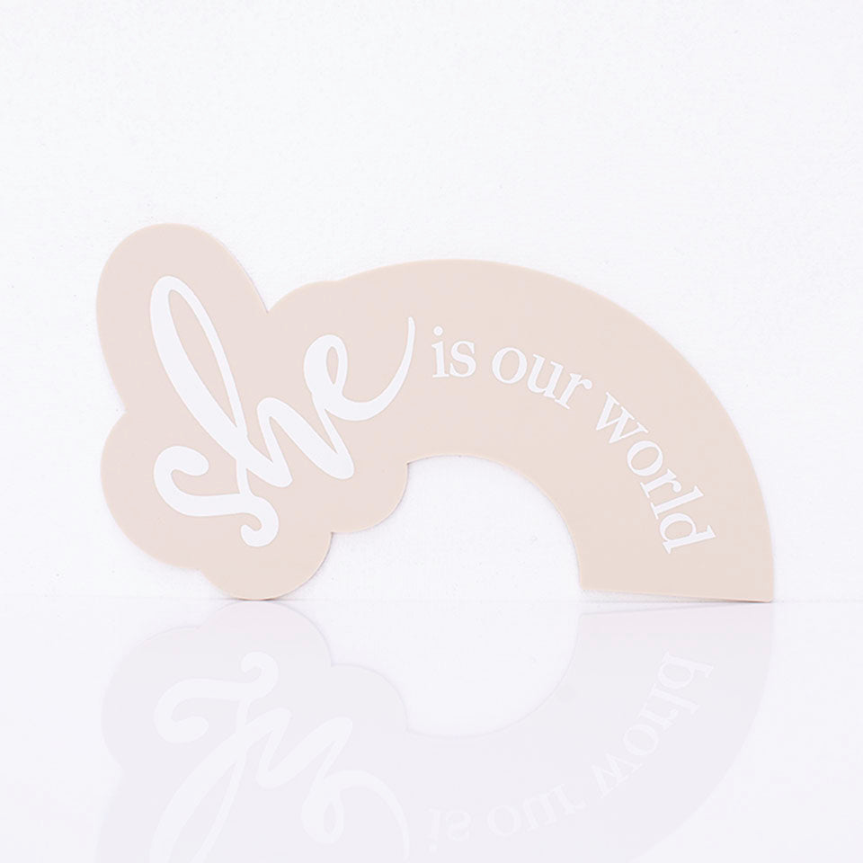 Hello Fern beige acrylic arch-shaped birth announcement plaque printed with the words "she is our world".