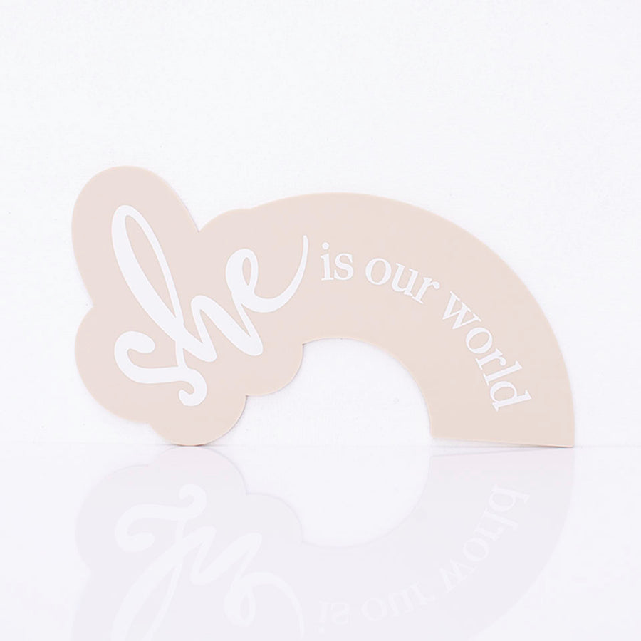 Hello Fern beige acrylic arch-shaped birth announcement plaque printed with the words "she is our world".