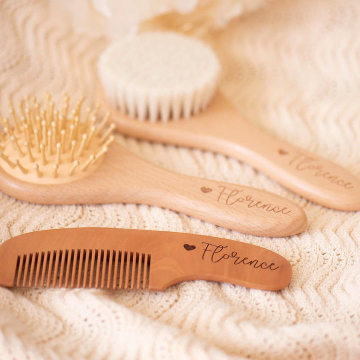 Wooden baby brushes and comb with 'Florence' and heart engraving on a textured surface