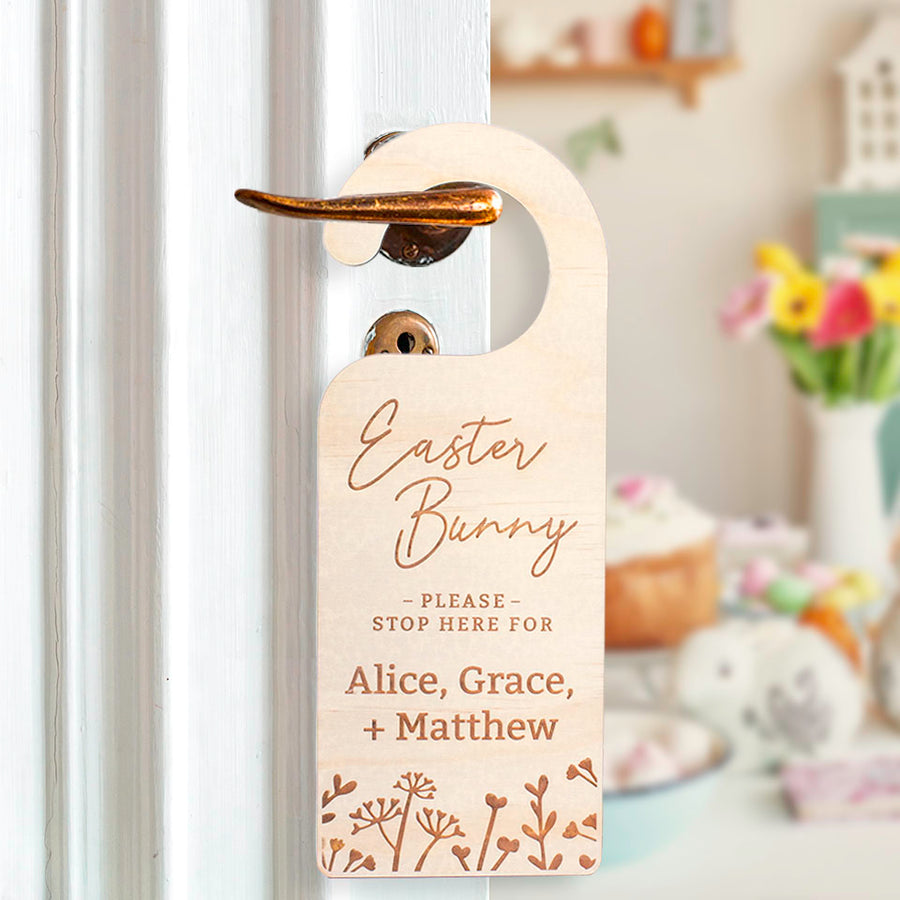 Hello Fern Easter Bunny please stop here for Alice, Grace, and Matthew wooden door hanger hanging on door knob and showing a blurred view of the kitchen with Easter decor on the table.