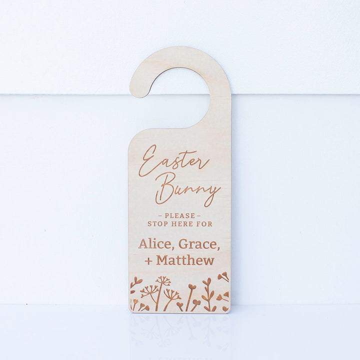 Hello Fern Easter Bunny please stop here wooden door hanger with multiple childrens' names isolated on white background.