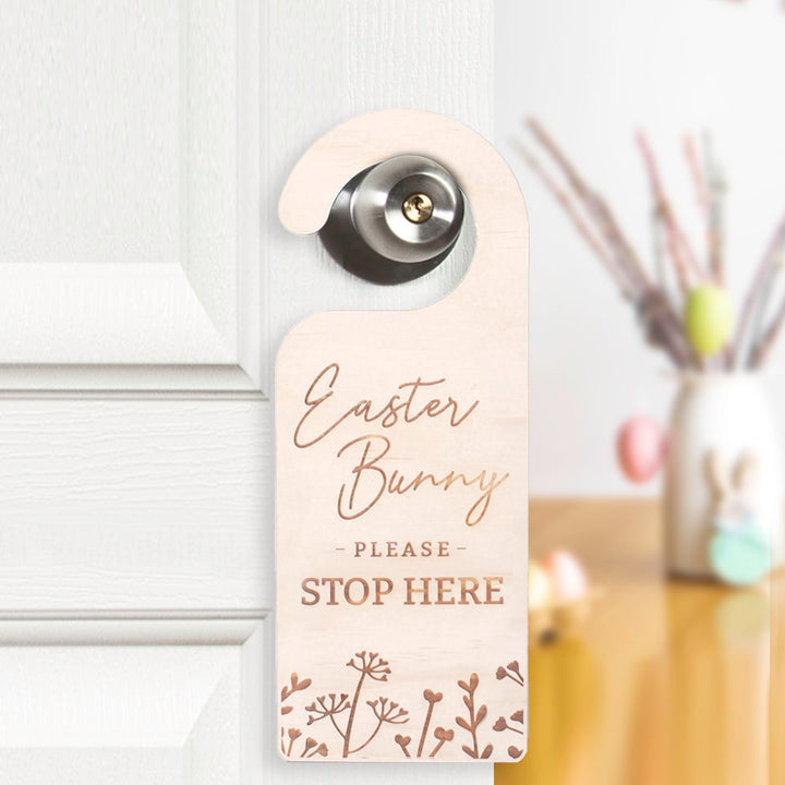 Hello Fern Easter Bunny please stop here non-custom wooden door hanger hanging on door knob and showing a blurred view of the kitchen with Easter decor on the table.