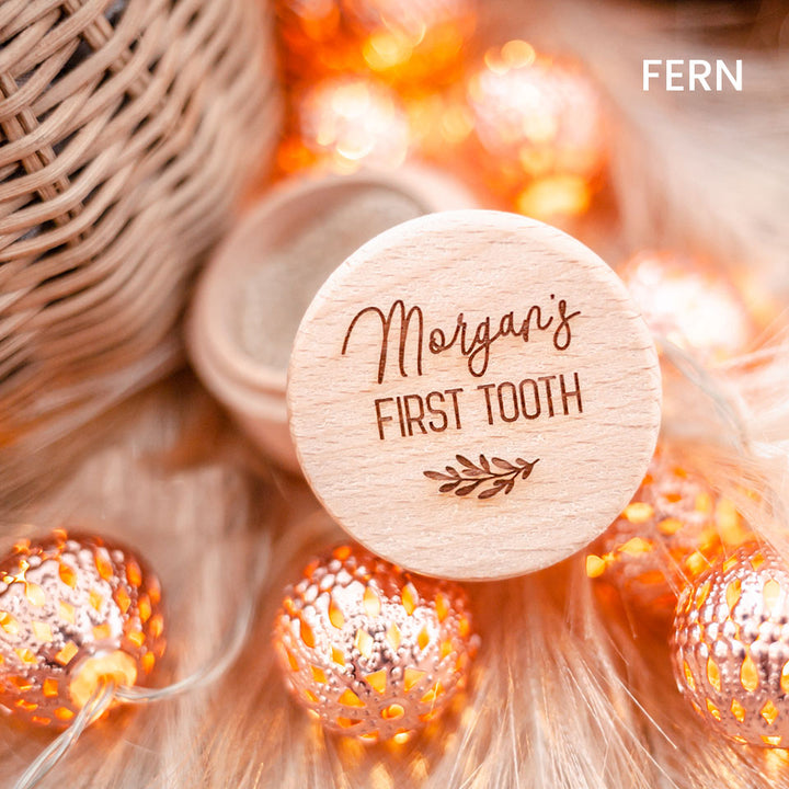 Closeup of Hello Fern baby's first tooth wooden trinket box customised with name shown with lid open and surrounded by ornamental lights.
