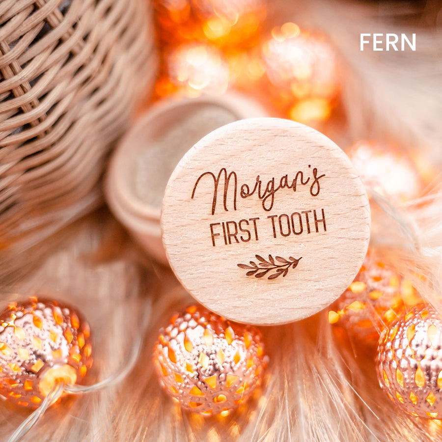 Closeup of Hello Fern baby's first tooth wooden trinket box customised with name shown with lid open and surrounded by ornamental lights.