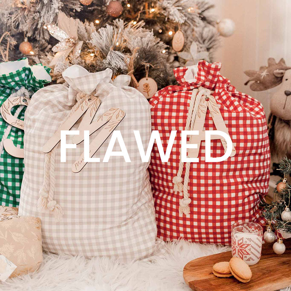 Set of three custom gingham Christmas Santa gift sacks in front of a Christmas tree.