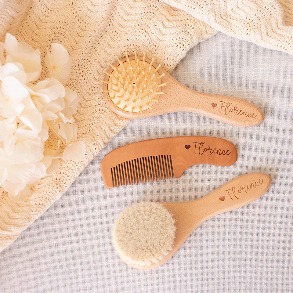 Set of wooden baby brushes and comb custom etched with 'Florence' and heart on a soft, textured fabric background.