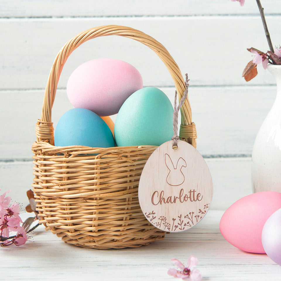 Hello Fern egg-shaped wooden Easter Basket Tag hanging on Easter basket with colourful eggs.