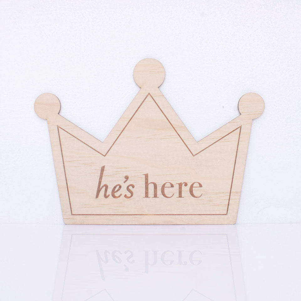 Hello Fern double-sided wooden birth announcement plaque in the shape of a crown displaying the side with the words "he's here".