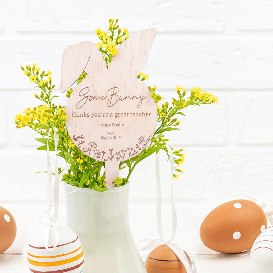 Hello Fern wooden Easter Bunny plant stake shown in flower vase with eggs surrounding.