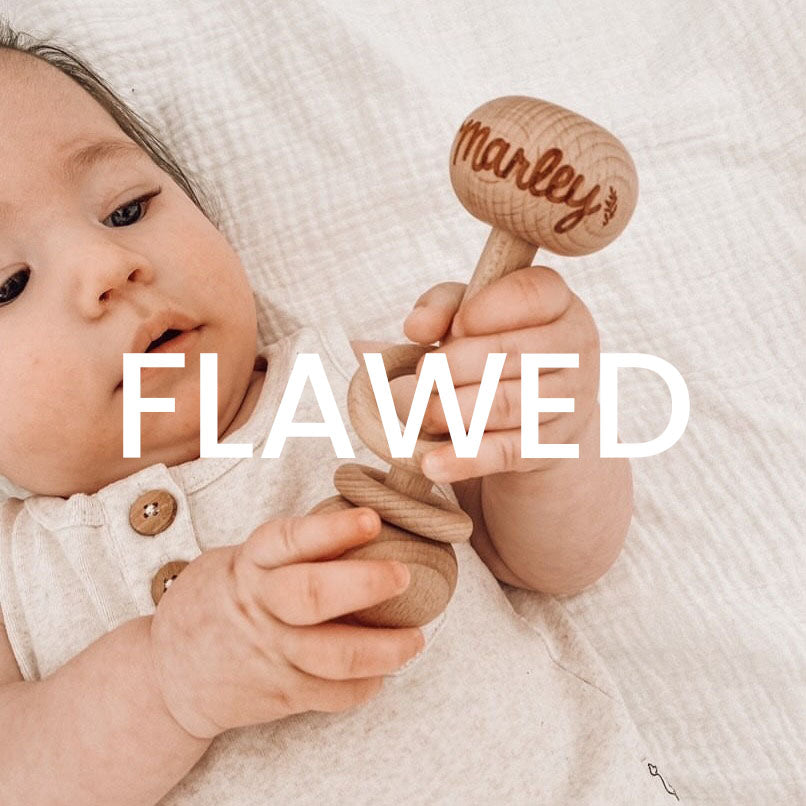 Baby Marley holding custom flawed wooden baby rattle with custom etched name.