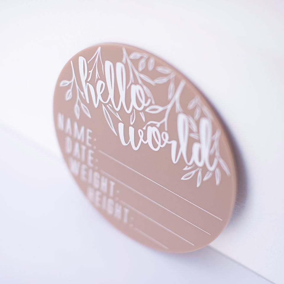 Cloesup of Hello Fern latte acrylic 'Hello Word' plaque with spaces for baby's name, birth date, weight, and height isolated on white background.