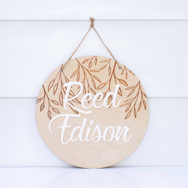 Hello Fern wooden and acrylic 3D name plaque with the name 'Reed Edison' in white acrylic, adhered to an etched wooden disc hanging on a white background.