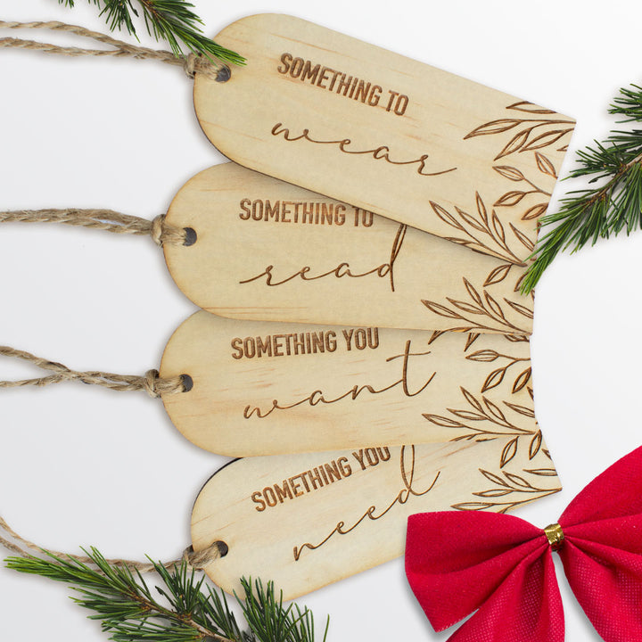 Set of four Hello Fern mindful giving gift tags shown as a flat lay with pine branches and a red ribbon.