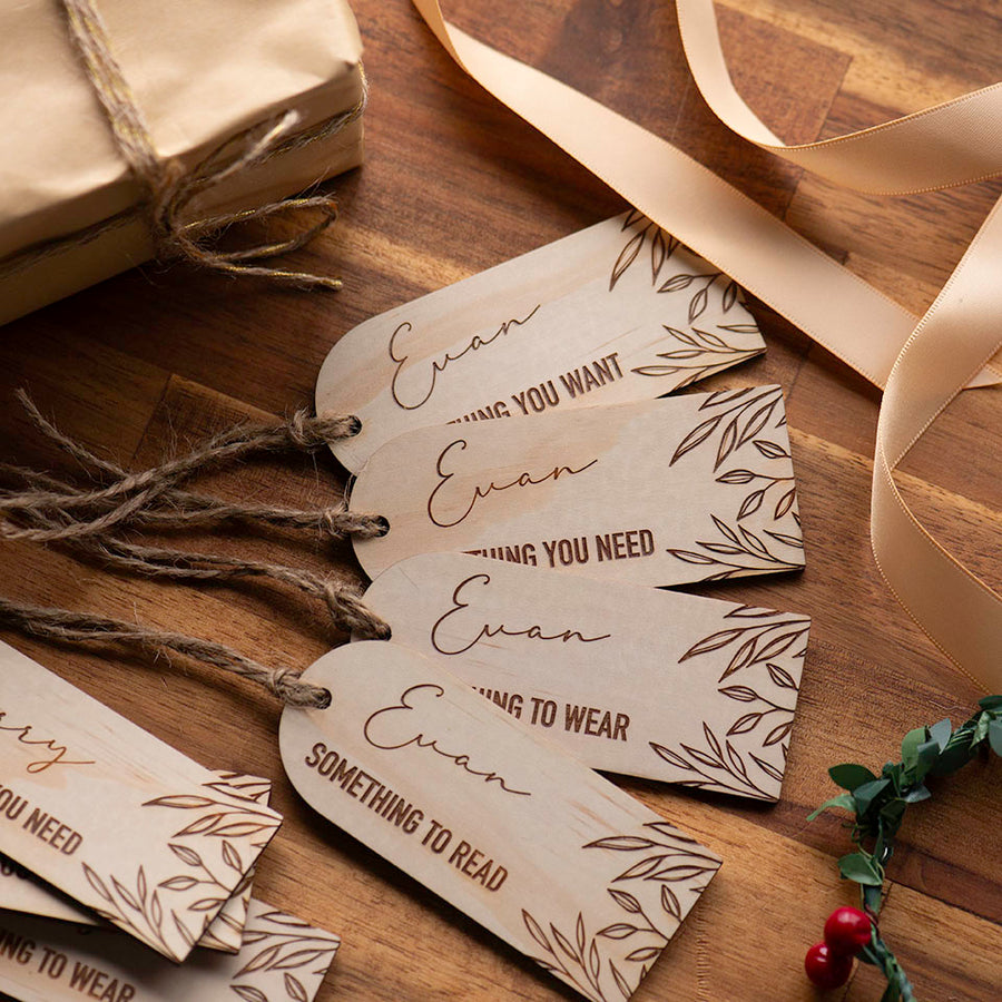 Top view of Hello Fern mindful gifting gift tags including 'something to wear', 'something to read', 'something you want', and 'something you need' with Christmas ribbon and gifts surrounding..