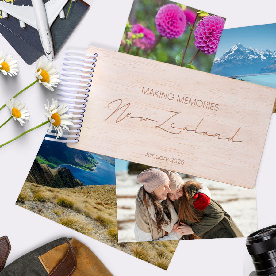 Hello Fern mini wooden travel-themed photo album with 'Making Memories New Zealand' text, surrounded by scenic photos and flowers.