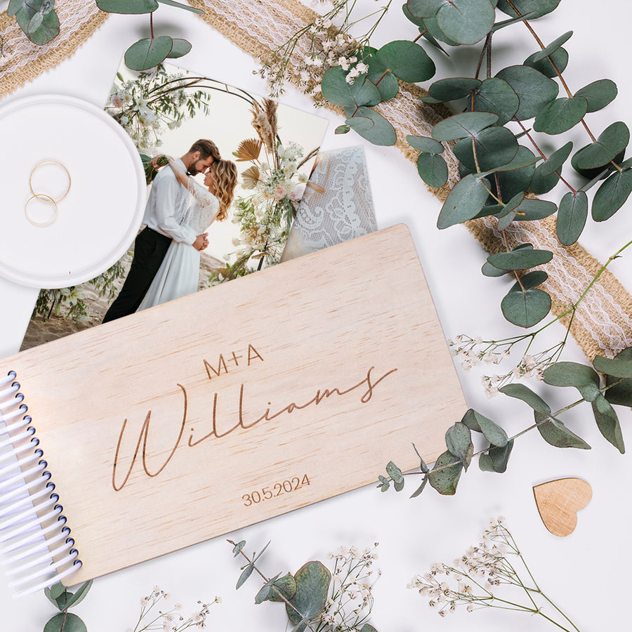 Hello Fern custom mini wooden photo album flat lay with wedding theme, rings, photos, and leaves.