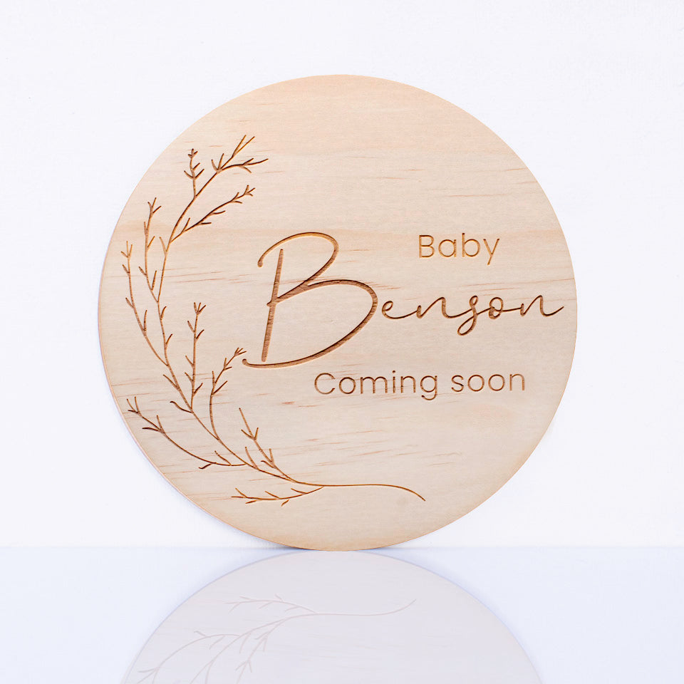Hello Fern personalised round wooden plaque with 'Baby Benson Coming soon' text on a white background.