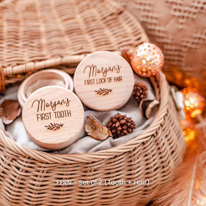 Set of two of Hello Fern wooden trinket boxes including baby's first tooth and first lock of hair, both customised with laser-engraved name sitting in woven basket.