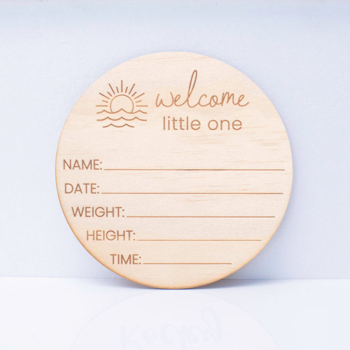 Hello Fern round wooden ocean-themed baby birth announcement plaque with engraved text "welcome little one" and placeholders for baby details on a white background.