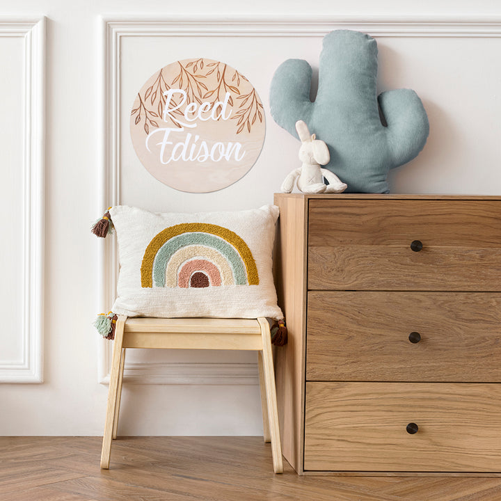 Hello Fern large wooden and acrylic 3D name plaque shown hanging on wall in child's bedroom with rainbow cushion, dresser, chair, and stuffed toys.