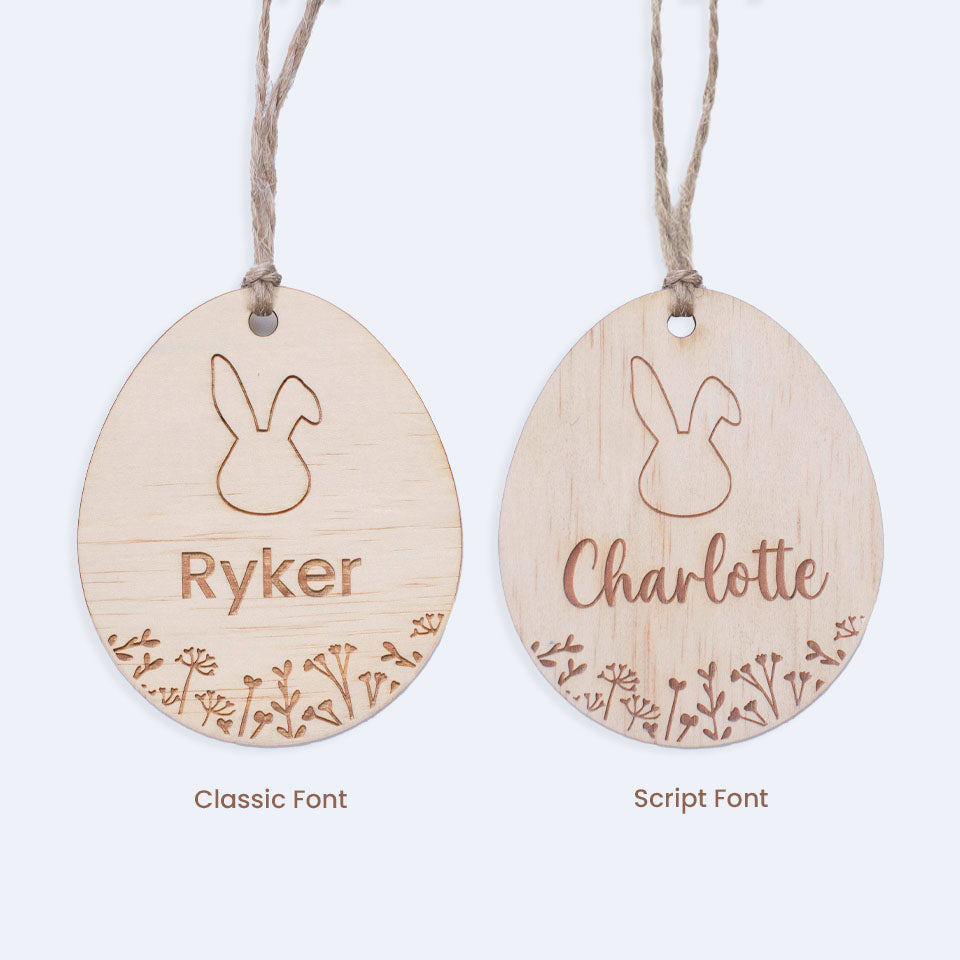 Set of two Hello Fern egg-shaped wooden Easter basket name tags depicting two font choices isolated on white background.