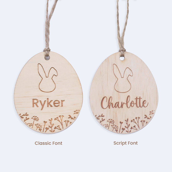 Set of two Hello Fern egg-shaped wooden Easter basket name tags depicting two font choices isolated on white background.
