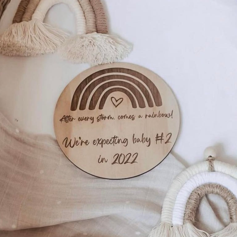 Closeup of Hello Fern wooden announcement disc in rainbow design with custom text.