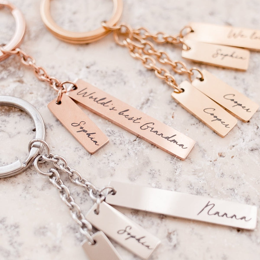 Closeup of silver, gold, and rose gold Mother's Day keyrings custom etched with grandmother and grandchildren's names.